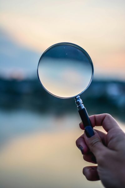 pexels-photo-1194775-1194775 A magnifying glass held by a hand outdoors at sunset, focusing on exploration.